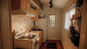 A compact kitchen with a stove, sink, and a window. - Bears Paw Duplex Cabin (#12) at The Woolly Bugger Inn (Estes Park)