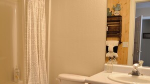 A bathroom with a toilet, a sink, a mirror, and a shower curtain.