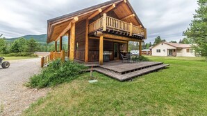 Eine Holzhütte mit Veranda, Grill und Rasenfläche.