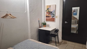 A compact room with a bed, a desk, a chair, and a door.