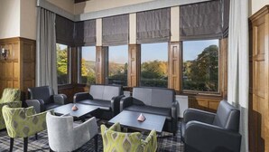 A room with large windows, a fireplace, and a seating area with tables and chairs. - Caledonian Hotel (Fort William)