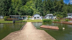 A wooden dock leading to a lake with houses on the opposite shore.