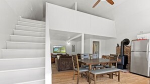 A modern kitchen with a dining area, a fireplace, and a staircase leading to an upper level.