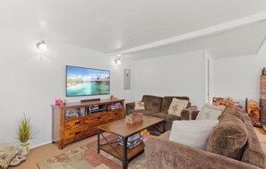 Ein Wohnzimmer mit einem großen Flachbildfernseher, einer Holzkommode, einem braunen Sofa und einem Couchtisch.