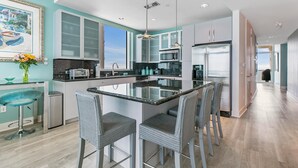 A modern kitchen with a central island, bar stools, and a view of the outdoors. - 3/3 Sapphire Condo 23rd Floor, Ocean & Bay View Balconies, Corner Unit, NO FEES! (South Padre Island)