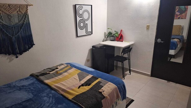 Ein Schlafzimmer mit einem Bett, einem Schreibtisch, einem Stuhl und einer Tür.