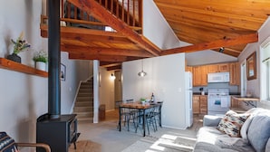 A spacious living area with a fireplace, a dining table, and a kitchen in the background.