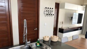 Eine moderne Küche mit einer Edelstahlspüle, Holzschränken und einem Essbereich mit Tisch und Stühlen.