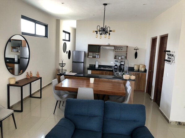 A modern kitchen with a dining area, a large mirror, and a blue sofa. - Casa Luz Downtown Apartments Tulum (Tulum)