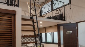 Eine Treppe mit Metallgeländer führt zu einem Erkerraum. Darunter befindet sich eine Essecke mit Tisch und Stühlen.