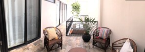 A small patio area with wicker chairs, a potted plant, and a table. - Casa Luz Downtown Apartments Tulum (Tulum)