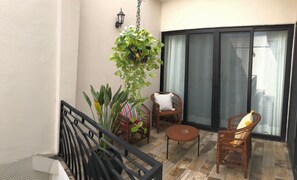 A balcony with a black railing, two wicker chairs, a small round table, and a hanging plant. - Casa Luz Downtown Apartments Tulum (Tulum)