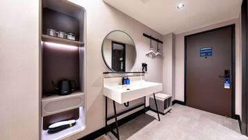 A modern bathroom with a white sink, a mirror, a towel rack, and a shelf with toiletries.