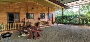 Une cabane en bois avec un patio couvert, une table de pique-nique et un chien allongé par terre.