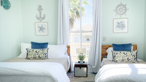 Ein Zimmer mit zwei Betten, einem Fenster mit Vorhängen und einer Wandgestaltung im maritimen Stil.