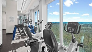Une salle de sport équipée de matériel d’exercice et dotée de grandes fenêtres donnant sur l’extérieur.