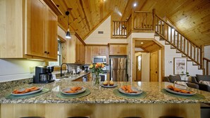 A spacious kitchen with granite countertops, wooden cabinets, and a central island with seating. - ❤️Heart of Hochatown | Modern Fam Friendly Cabin, Fun Games, Hottub, Firepit ✨ (Broken Bow)