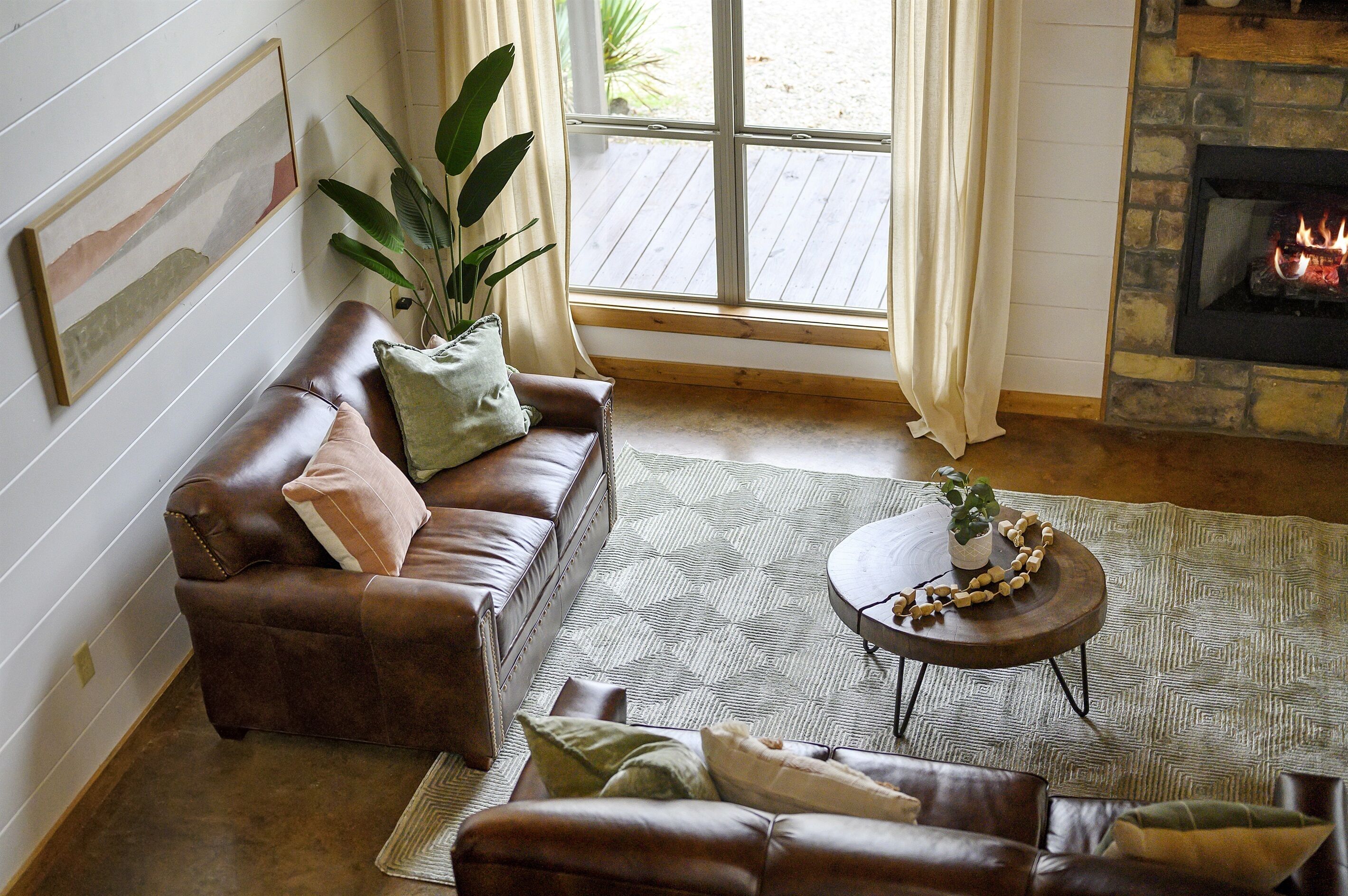 Un salon chaleureux avec un canapé en cuir, un tapis à motifs, une table basse ronde et une cheminée.