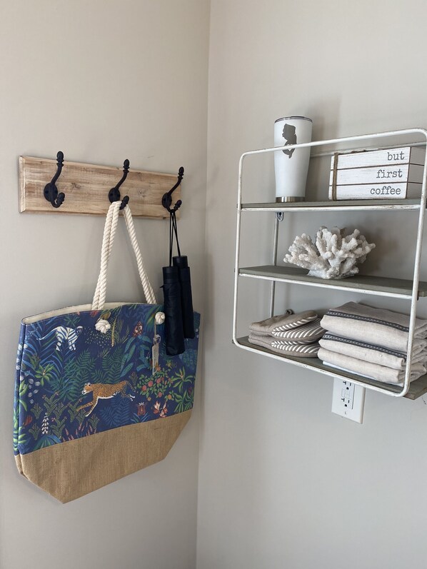 A wall-mounted shelf with a coffee mug, a decorative coral, and folded towels. - Cozy cottage on iconic tree lined Washington Street (Cape May)