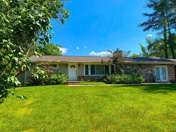 A single-story house with a stone facade, a front porch, and a well-maintained lawn.