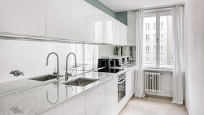 A modern kitchen with white cabinets, a marble countertop, and a window with curtains. - Dreamy Innere Stadt 2BR w/ Elevator, steps to Hoher Markt, by Blueground (Vienna)