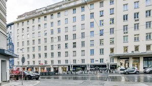 A multi-story hotel with a uniform facade, ground-level shops, and a parking area. - Dreamy Innere Stadt 2BR w/ Elevator, steps to Hoher Markt, by Blueground (Vienna)