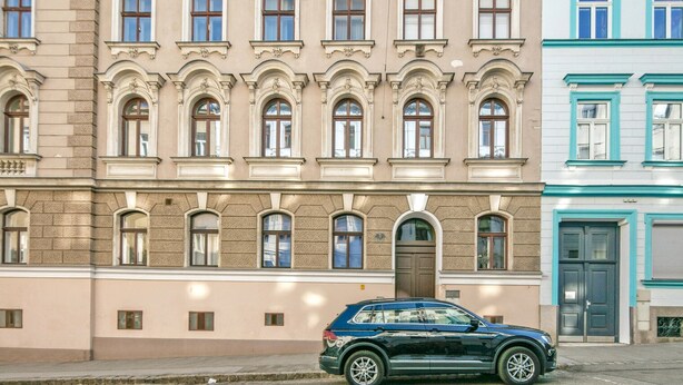 Un edificio de varios pisos con un estilo arquitectónico clásico, con ventanas en arco y molduras decorativas.