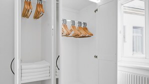 Un armario vestidor blanco con perchas de madera y toallas dobladas con cuidado.