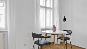 Una habitación con una mesa redonda, dos sillas, un jarrón y una lámpara de pie.