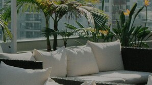 Un balcón con sofá y plantas en macetas, con vistas a un paisaje urbano.