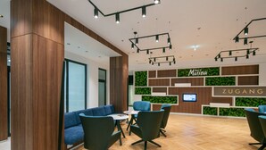 Un moderno vestíbulo de hotel con mostrador de recepción, zona de estar y paneles de madera.