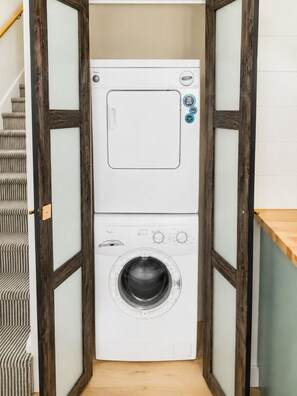 A compact, two-door laundry room with a built-in washer and dryer, wooden framing, and a small countertop. - Jiminy Peak Resort - Walkable - Heated Pool + Hot Tub - Fireplace (Hancock)