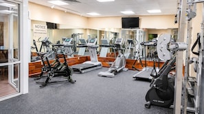 Una palestra con diverse attrezzature per esercizi, tra cui tapis roulant, cyclette e macchinari per pesi.