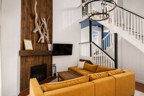 A living room with a sectional sofa, a fireplace, a mounted TV, and a staircase with a modern design. - Jiminy Peak Resort Townhome, Sleeps 10, Pool, Hot Tubs, Sauna & Deck (Hancock)