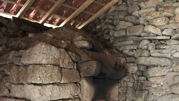 A stone oven with a fire burning inside, surrounded by stone walls.