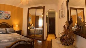 Una camera da letto con un letto, comodini, uno specchio e un'opera d'arte floreale appesa al muro.