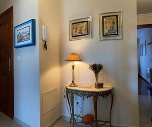 A hallway with a table lamp, a vase with flowers, and three framed pictures on the wall. - VOLVORETA APARTMENT in the center of O Grove.             (Grove, O (Casco Urbano))