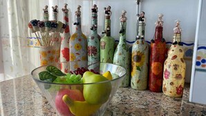 Un ripiano della cucina con una ciotola di frutta e bottiglie colorate.