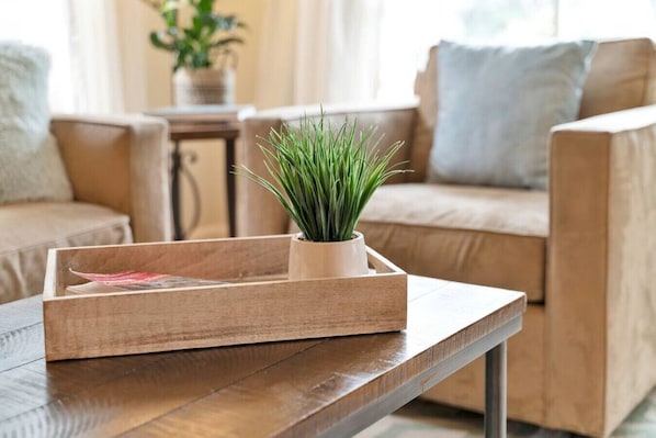 A wooden tray with a potted plant on a wooden table in a living room.