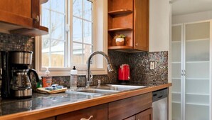 A kitchen with wooden cabinets, a stainless steel sink, a coffee maker, and a red kettle. - Mellow Yellow UW & Children's  Free parking! (Seattle)