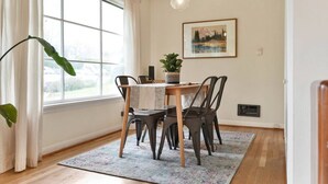 A dining area with a table, chairs, a potted plant, and a painting on the wall. - Mellow Yellow UW & Children's  Free parking! (Seattle)