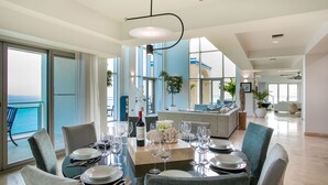 A dining area with a table set for six, large windows, and a view of the ocean. - The Cove | Beach Front - Located in  Exquisite Simpson Bay with House Cleaning Included (Lowlands)