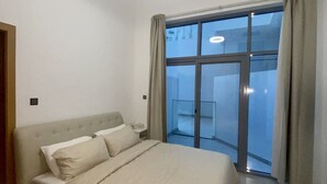 Een slaapkamer met een bed, een plafondlamp, een raam met gordijnen en uitzicht op de omgeving.