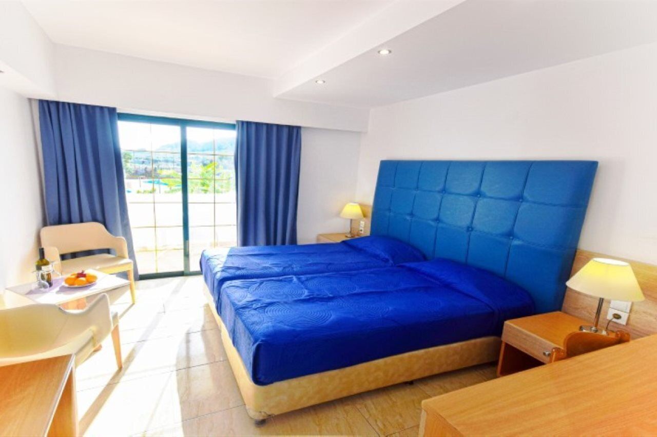 A hotel room with a large bed, a desk, a chair, and a view of the outdoors.