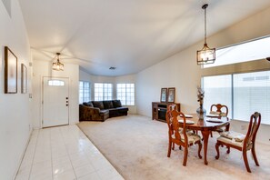 A spacious living room with a large window, a dining area with a wooden table and chairs, and a cozy seating area with a sofa and a fireplace.