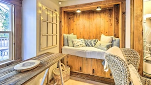 A cozy room with a wooden bench, a cushioned seating area, and a small table with a decorative plate. - Pet-Friendly Cabin: Minutes to Gig Harbor! (Fox Island)