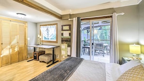 A bedroom with a bed, a desk, and a view of an outdoor patio. - Pet-Friendly Cabin: Minutes to Gig Harbor! (Fox Island)