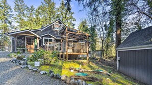 A cabin with a wooden deck, a covered porch, and a gravel driveway. - Pet-Friendly Cabin: Minutes to Gig Harbor! (Fox Island)