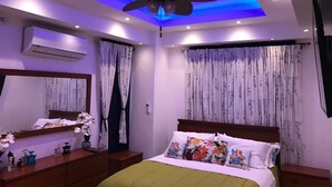 Une chambre à coucher avec un lit, un ventilateur de plafond et des rideaux.