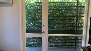 Een kamer met een schuifdeur die uitkomt op een balkon met uitzicht op groen.